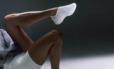 Person wearing a white sock with a textured pattern on a dark background